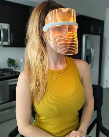 Woman in kitchen using Derma Therapy Mask on amber light